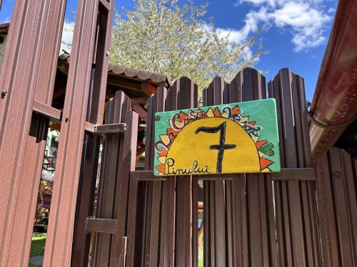 a sign on a wooden fence with a clock on it at La Casa Verde in Buşteni