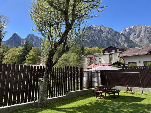 a wooden fence with a picnic table and a tree at La Casa Verde in Buşteni
