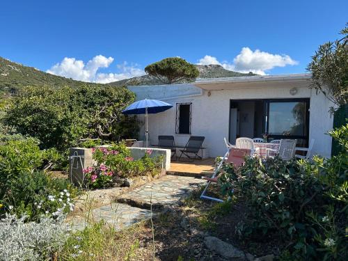 une maison avec une terrasse et un parasol dans l'établissement Maison les pieds dans l'eau, à Lumio