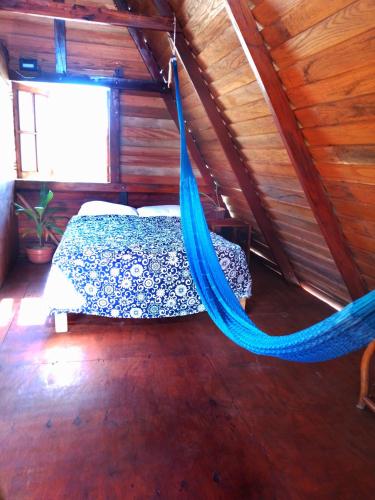 a bed in a room with a blue hammock at Hospedaje Wotoch Aayin in Venecia