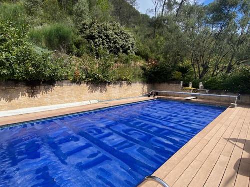 a large blue swimming pool with a wooden deck at La Maison Vieille in Peillon