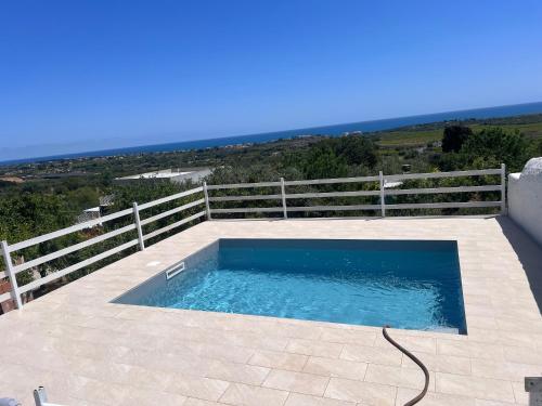 a swimming pool on a patio with a fence at Agriturismoeloropizzuta in Noto Marina