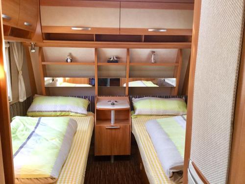 Kleines Zimmer mit 2 Betten und einem Waschbecken in der Unterkunft Luxoriöser Wohnwagen 400 Meter vom Meer in Grömitz. in Lenste