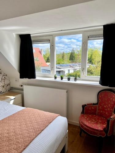 a bedroom with a bed and a chair and windows at The Grutto, private apartment 25 min from city center in Amsterdam