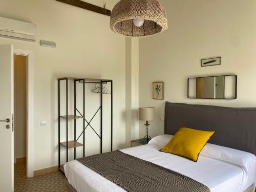 a bedroom with a bed with a yellow pillow at Les Filles (antiga Fonda de la Parra) in Deltebre