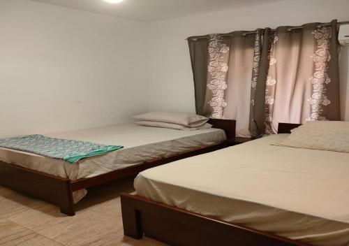 a room with two beds and a window with curtains at Blumar Sidi Abdel Rahman 2 bedrooms Chalet North Coast in El Alamein
