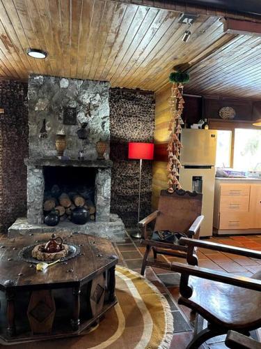 a living room with a stone fireplace and a table at María Ce - Cabaña familiar en el K25 vía al mar in Papagalleros