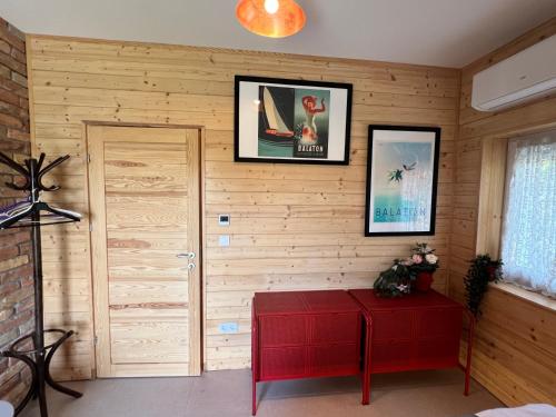 a room with a wooden wall with a door and a red table at NEON Apartman Csopak Balaton, large botanical garden, bicycles, pet&family friendly, outside kitchen, in Csopak