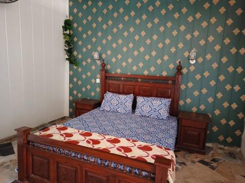 1 dormitorio con cama de madera y pared verde en Kashmir Cottage Muzaffarabad en Muzaffarābād