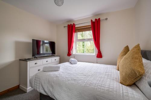 a bedroom with a bed and a tv and a window at Stylish & spacious 3 bedroom entire house in Lisburn with parking in Lisburn