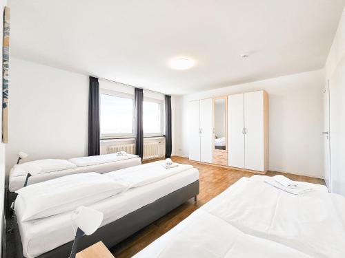 a bedroom with three beds and a large window at Tolstov Apartments - 1 or 3 Room Apartments with Balcony - 20 Min Messe DUS & Airport DUS in Meerbusch