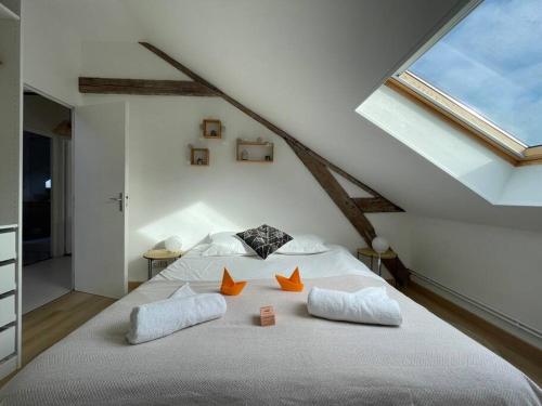 une chambre avec un lit blanc avec des oreillers orange dans l'établissement Le Monde d'Elodie - Rouen Gare routière, à Rouen