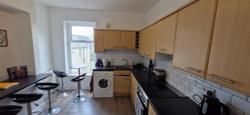 a kitchen with wooden cabinets and a washing machine at Large Three Bedroom Apartment with Roof Terrace Near City Centre in Cardiff