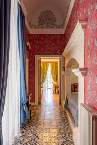 a bedroom with red wallpaper and a bed and a hallway at Villa in Gargano - VILLA BASSO in Monte SantʼAngelo