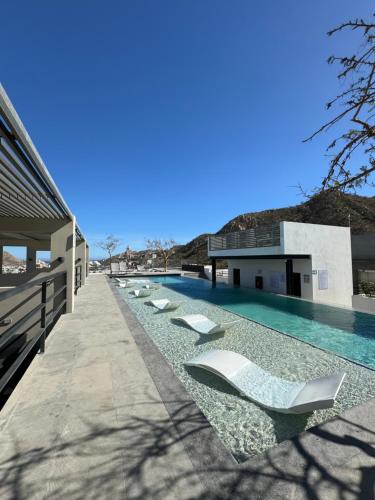 a swimming pool with lounge chairs next to a building at Live! Departamento céntrico con asombroso Rooftop y Alberca in Cabo San Lucas