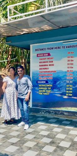 a man and a woman standing in front of a sign at ARABIAN HOLIDAY RESORT WITH SWIMMING POOL IN IDUKKI Calvary Mount in Idukki