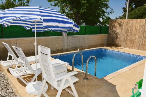 a pair of chairs and an umbrella next to a swimming pool at Villa Kayacık in Dalaman