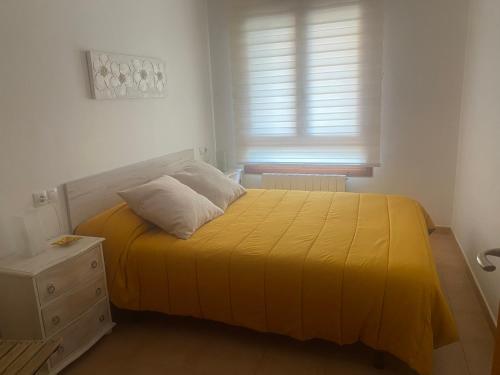 - une chambre avec un lit doté d'un couvre-lit jaune dans l'établissement Apto en Campo Valle de Benasque 2 dormitorios Wifi, à Campo