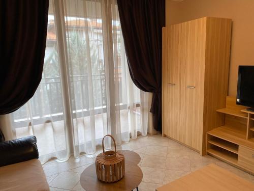AJ Apartment 2, Santa Marina Holiday Village, Sozopol في سوزوبول: غرفة معيشة مع طاولة ونافذة كبيرة