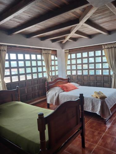 dwa łóżka w pokoju z oknami w obiekcie Chez Alicia Hostal w mieście Villa de Leyva