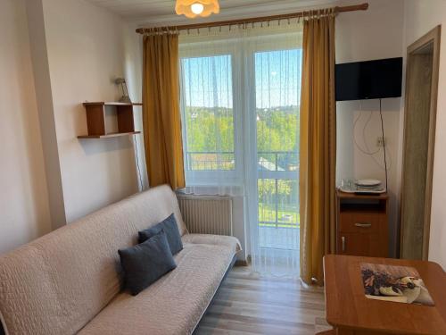 a living room with a couch and a large window at Nad Bieszczadzkim Morzem in Polańczyk