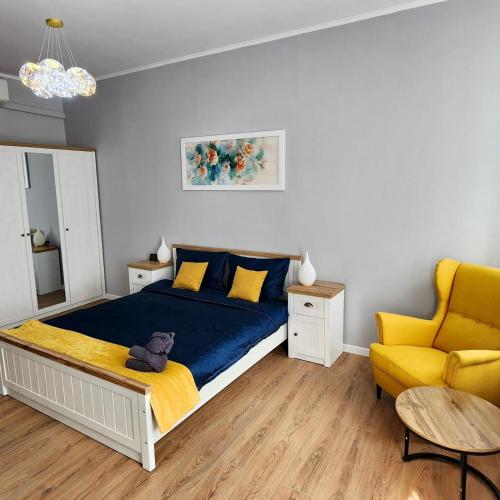 a bedroom with a bed and a yellow chair at City Center apartment -A in Cluj-Napoca