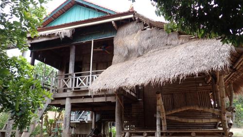 的住宿－OBT - The Longan Bungalow，一座带稻草屋顶和阳台的建筑