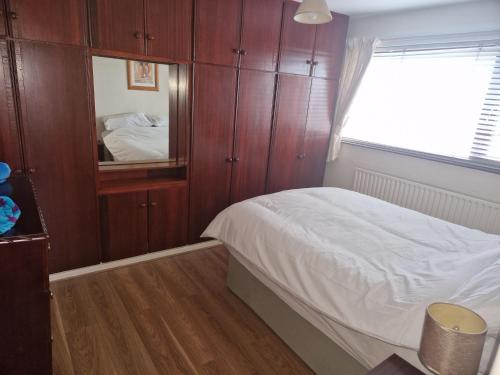 a bedroom with wooden cabinets and a bed with a mirror at Home from Home in Belfast