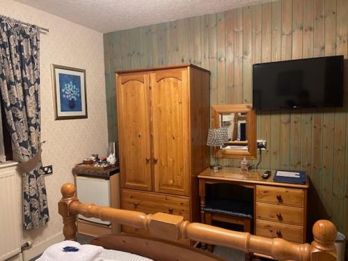 a bedroom with a television and a wooden cabinet at Dionard Guest House in Inverness