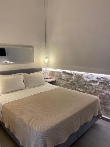 a bedroom with a bed and a wall with rocks at AVALON Luxury Suites in Ermoupoli
