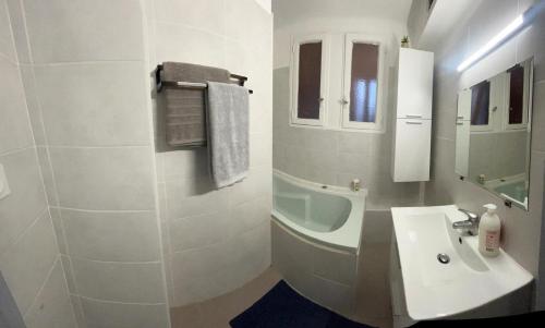 une salle de bain blanche avec un lavabo et un miroir dans l'établissement Appartement Montpellier Sud 3 pièces, à Montpellier
