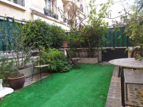 un jardin avec une pelouse verdoyante devant un bâtiment dans l'établissement Le Jardin de la Faisanderie, à Paris