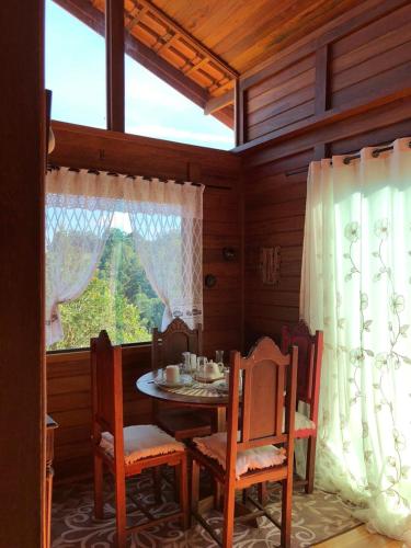 a dining room with a table and chairs and a window at Chalé Sonho Diniz 2 in Monte Verde