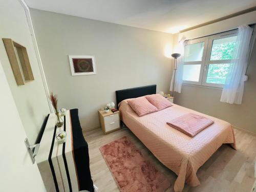 una camera da letto con un letto con lenzuola rosa e una finestra di Joli T2 classé 1* Plaisir Gare direct Paris a Plaisir
