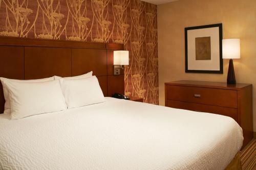 a hotel room with a large bed with white pillows at Courtyard Des Moines West/Clive in Clive