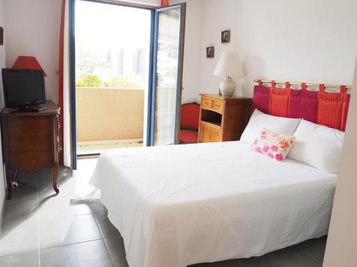 une chambre avec un lit blanc et une télévision dans l'établissement Colore di mar, à Cavalaire-sur-Mer