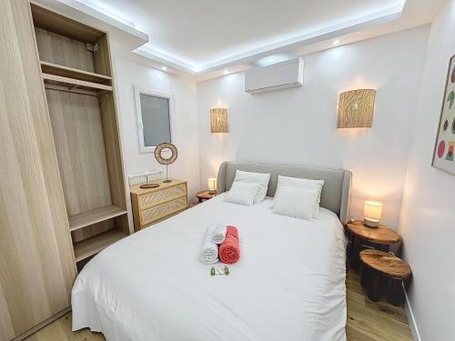 une chambre avec un lit blanc avec des draps blancs et des fleurs dessus dans l'établissement 50m2 Croisette Martinez, Terrasse vue mer, à Cannes