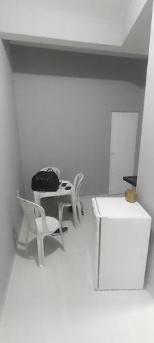 een witte kamer met 2 stoelen en een tafel en een tas bij Kitnet in Fortaleza