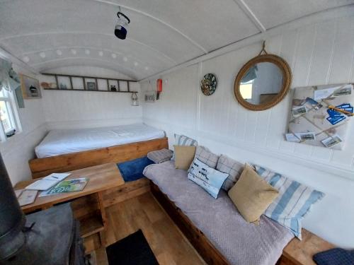 a living room with a couch and a bed in a trailer at Meadowbeck - Shepherd Huts in Fylingdales