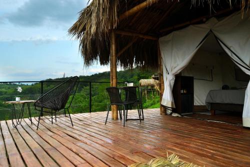 una terraza con una tienda de campaña con sillas y una mesa en Encanto Toscano, en Quimbaya