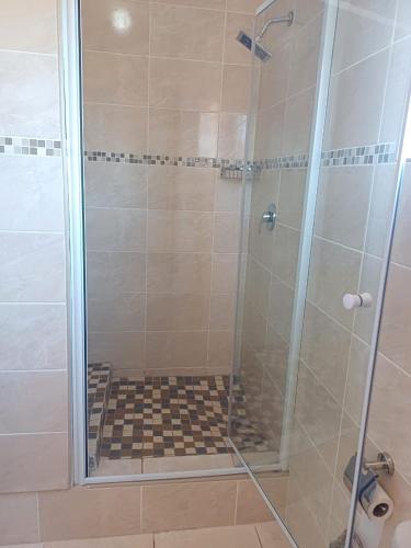 a bathroom with a shower with a glass door at Thokgamo Bed and Breakfast in Kanye