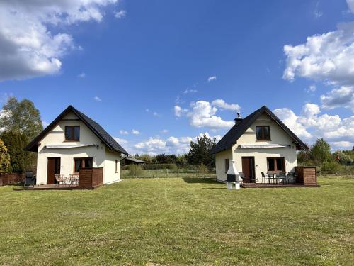 dos pequeñas casas blancas sentadas en un campo de hierba en Leszczynowe Zacisze, en Wiele