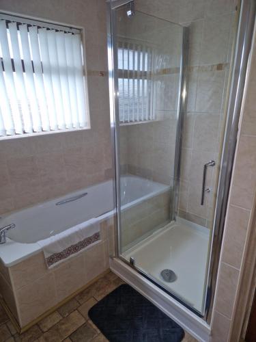 a bathroom with a shower and a bath tub at Home from Home in Belfast