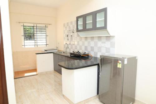 a kitchen with a counter and a refrigerator in it at HSR Parkside by Newstays in Bangalore