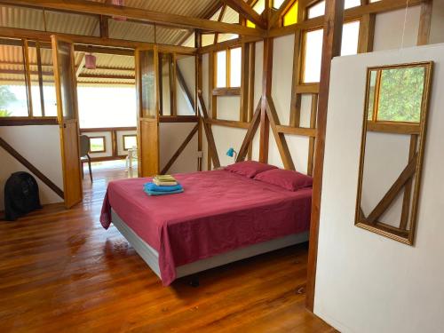 ein Schlafzimmer mit einem Bett in einem Zimmer mit Holzböden in der Unterkunft Jardin Pacifico in Canoa