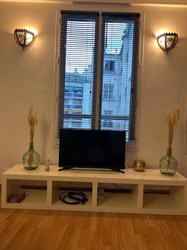 un salon avec une télévision sur une table dans l'établissement Havre de paix Paris 9, à Paris