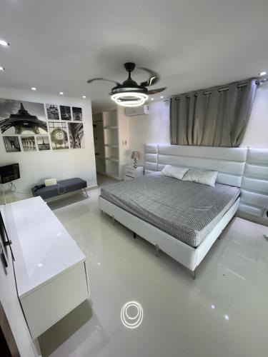 a white bedroom with a bed and a table at Villa 1 in Santo Domingo