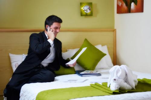 a man sitting on a bed talking on a cell phone at Kuna Hotel in Cuenca