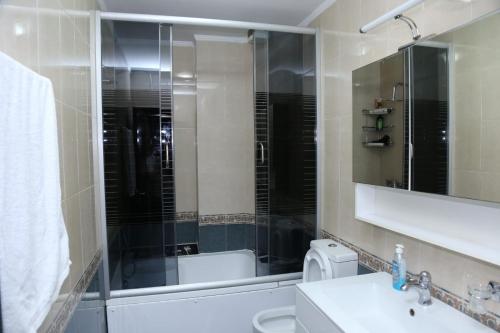 a bathroom with a sink and a toilet and a mirror at Ergi’s Host Apartment in Tirana