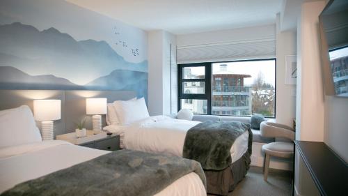 a hotel room with two beds and a window at Carleton Lodge in Whistler